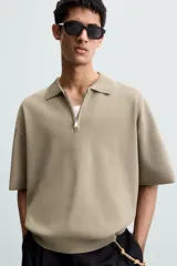 Polo de punto color verde oliva, de manga corta y corte relajado. Presenta cuello solapa con cierre frontal de cremallera.