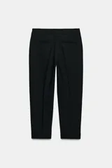 Pantalón de tiro alto color beige, de corte recto y largo tobillero, con bolsillos laterales y cierre frontal con cremallera y ganchos metálicos.