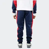 Pantalón de jogging azul marino de felpa, con franjas laterales en rojo y blanco. Presenta el escudo del Club Nacional de Football en el muslo derecho y el logo de Umbro en el izquierdo, con cintura elástica y cordón de ajuste.