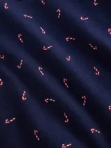 Conjunto de pijama compuesto por una camisa de manga larga con cuello solapa, cierre frontal de botones y bolsillo en el pecho, y un pantalón de corte recto con cintura elástica. Ambas piezas presentan un estampado de pequeños motivos oscuros sobre fondo claro y detalles de ribetes en contraste.