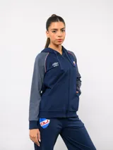 Campera deportiva con capucha y cierre frontal, de la marca Umbro para el Club Nacional de Football. Presenta un diseño en azul marino con mangas en tono gris jaspeado, detalles de vivos tricolores en los hombros y el escudo del club bordado en el pecho.