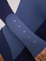 Malla entera de manga larga con cierre frontal, confeccionada en combinación de tonos azul marino y azul medio, con logo de la marca estampado en el pecho.