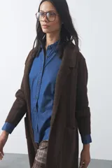 Cardigan largo de tejido suave color marrón, con diseño abierto, mangas largas y bolsillos frontales aplicados.