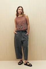 Pantalón de algodón color gris oscuro, estilo baggy o ancho, con cintura elástica y cordón ajustable. Presenta costuras marcadas que definen paneles en la pierna y puños ajustados en el tobillo.