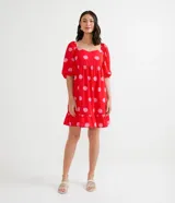 Vestido corto rojo con estampado de lunares rosas, escote cuadrado, mangas cortas abullonadas y volado en el ruedo.