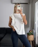 Blusa blanca de símil lino con cuello redondo fruncido, doble volado en las mangas con detalle de encaje.