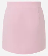 Short pollera de sastrería color rosado, con diseño asimétrico superpuesto en el frente, bolsillos ribeteados decorativos y cierre lateral discreto.