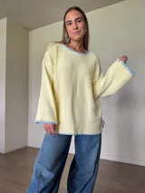 Sweater de punto jersey de algodón color amarillo con silueta oversize, mangas acampanadas y cuello a la base. Presenta terminaciones hechas a mano en crochet a contratono en color celeste con detalles de lurex.
