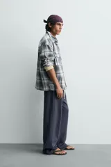 Camisa de algodón de corte relajado, con cuello solapa, manga larga terminada en puño con botón y dos bolsillos de plastrón con solapa en el pecho. Presenta un estampado de cuadros en tonos azules, grises y blancos, y cierre frontal de botonadura.