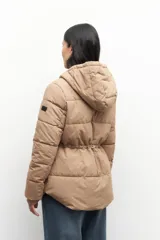 Campera puffer color tostado con capucha, cierre frontal con botones a presión y bolsillos laterales. Presenta diseño acolchado, puños elásticos y ajuste en la cintura.