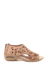 Sandalia baja de cuero color beige, con diseño cerrado en el empeine y talón, decorado con perforaciones circulares de distintos tamaños. Cuenta con suela de goma con cámara de aire en el talón.