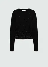 Jersey de punto fino color negro, con cuello redondo y manga larga. Presenta un diseño crop con aplicación de strass distribuido por toda la prenda.