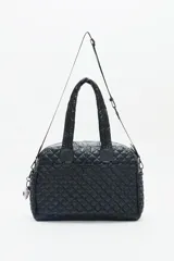 Bolso tipo shopper color marrón con diseño matelassé. Tiene doble asa corta y correa larga desmontable. Incluye llavero de corazón y dijes desmontables, y compartimento interior para notebook.