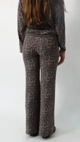Conjunto de dos piezas compuesto por un sweater de cuello redondo y mangas largas holgadas, y un pantalón de corte recto, ambos confeccionados en tejido acanalado con estampado animal print de leopardo en tonos marrones y grises.
