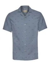Camisa de manga corta color azul marino con estampado de peces pequeños. Presenta cuello tipo cubano y cierre frontal con botones.