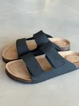 Sandalias negras con dos tiras anchas con costuras en forma de X, plantilla de corcho y suela de goma.