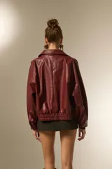 Campera estilo biker de eco-cuero color bordó, con cuello solapa ancho, manga larga y calce holgado. Presenta cierre frontal y botones decorativos en la parte inferior delantera.
