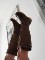 Botas altas de cuero marrón combinadas con gamuza blanca con estampado de vaca, forradas en cuero y con cierre de bronce.