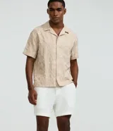 Bermuda de algodón blanca con textura cuadriculada, cintura elástica con cordón ajustable y bolsillos laterales.