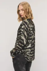 Camisa de viscosa con estampado animal print tipo zebra en tonos negros y grises, con diseño de cuello con lazo integrado, alforzas frontales con volados y mangas largas.
