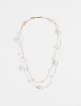 Collar de doble cadena fina dorada decorado con perlas blancas de diversos tamaños y formas irregulares.