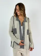 Saco de punto con cuello polo, botones frontales y bolsillos de parche. Diseño a rayas verticales en tonos beige y gris, con detalles en gris liso en el cuello, la tapeta de botones y los bolsillos.