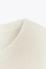 Jersey de punto color crema, confeccionado en 100% lana, con cuello redondo y mangas cortas anchas, de calce amplio.