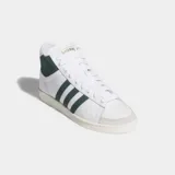 Championes Adidas modelo Jabbar Hi, de corte medio, con exterior de cuero blanco, detalles en gamuza verde oscuro en las tres tiras laterales y el cuello, y suela de goma color crema.