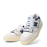 Championes urbanos New Balance modelo 550, con diseño de corte bajo inspirado en el básquet. Presentan una combinación de cuero y malla en tonos beige y azul marino, con suela de goma en tono crema envejecido.