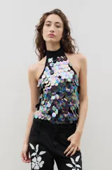Top estilo halter con cuello alto, confeccionado sobre una base negra y cubierto completamente por lentejuelas circulares iridiscentes de gran tamaño.