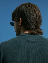 Remera de punto tipo polo con textura waffle, color verde petróleo, de manga larga y cuello con cierre de botones.