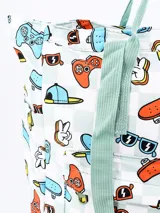 Mochila blanca con estampado de videojuegos, skateboards, lentes de sol y otros elementos. Tiene asas de mano y tiras para colgar en la espalda, ambas en color verde agua.