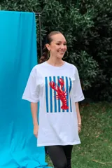 Remerón de algodón blanco con corte oversize y cuello redondo, que presenta un estampado frontal con diseño de una lata de sardinas sobre fondo de rayas.