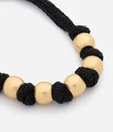 Collar maxi confeccionado con una combinación de tejido negro texturizado y grandes esferas metálicas doradas intercaladas.