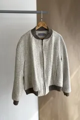 Campera estilo bomber color beige con textura, cierre delantero, cuello, puños y ruedo tejidos. Forrada, confeccionada en lana fina sin teñir.