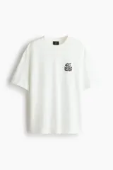 Remera de algodón blanca de corte holgado, con cuello redondo y un pequeño estampado gráfico negro en el pecho con el texto "NEXT LEVEL READY".