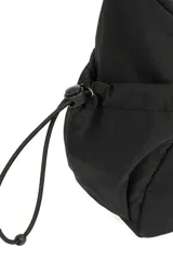 Bandolera de diseño funcional en color beige, confeccionada en poliéster. Presenta un compartimento principal con cierre, correa ajustable para el hombro y bolsillos laterales con cordón elástico regulable.