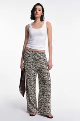 Pantalón de viscosa estampado con animal print de cebra en tonos beige y negro. Presenta cintura elastizada con lazo regulable y pierna recta.