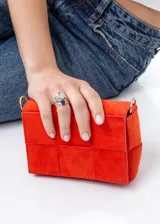 Mini bag color naranja con diseño acolchado tipo tejido, correa de hombro y cinto a juego.
