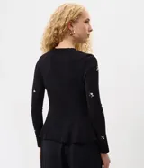 Cardigan negro de punto con bordado floral delicado, mangas largas, escote redondo, cierre frontal con botones y diseño peplum en la cintura.