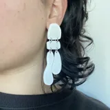 Aros colgantes color rojo con piezas geométricas irregulares unidas por argollas plateadas.