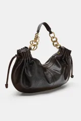 Bolso de hombro en color marrón oscuro con efecto craquelado. Presenta detalles fruncidos en los laterales con tiradores ajustables y un asa corta que combina una parte de material sintético con eslabones de cadena metálica dorada. Cuenta con un bolsillo interior y cierre mediante cremallera.