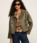 Trench coat corto de cuero sintético (PU) en color verde oliva, con cuello de solapa, cierre frontal de doble botonadura y mangas largas con detalle de trabillas en los puños.