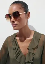 Vestido midi color verde militar, confeccionado en tejido fluido de poliéster. Presenta un diseño evasé, escote de pico con volantes, y mangas largas con puños elásticos. Incluye detalles de volantes en el cuello y forro interior.