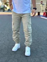 Pantalón jogger cargo beige de corte holgado, con bolsillos laterales con solapa en las piernas y puños elásticos en los tobillos.