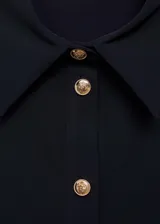 Vestido midi de color negro con cuello camisero y cierre frontal de botones dorados. Presenta mangas largas con puños abotonados, diseño entallado en la cintura con detalle drapeado y falda evasé.