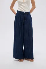 Pantalón jean azul de tiro medio, corte holgado y diseño amplio con pinzas en la parte frontal.