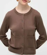 Cardigan de punto color beige, de corte clásico y manga larga, con cuello redondo, cierre frontal por botones y bolsillos delanteros funcionales.