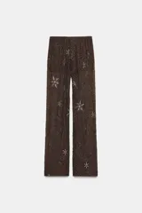 Pantalón de tiro alto, pierna recta y forro interior tipo shorts. Confeccionado en tejido negro con bordado floral en lentejuelas y abalorios dorados.