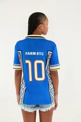 Camiseta deportiva Farm Etc. azul con cuello polo en tono crema y detalles negros, manga corta con líneas decorativas y estampado frontal con escudo y palmeras.